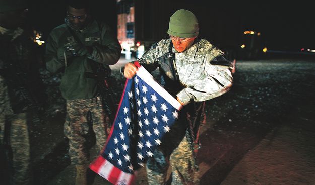 Az 1. lovas (harckocsizó) hadosztály katonája indulás előtt összehajtogatja a bevont amerikai zászlót