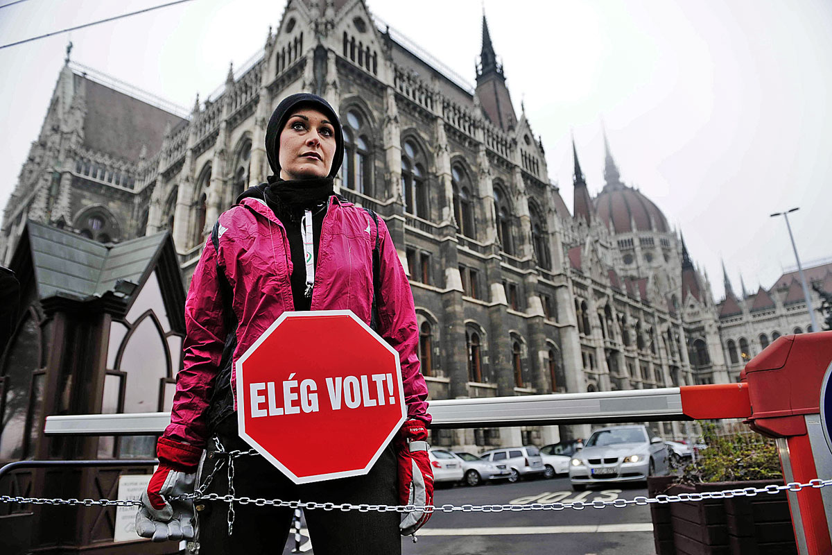 Kaufer Virág a parlament kapujához láncolva próbálja feltartani a kétharmados szavazógép működtetését