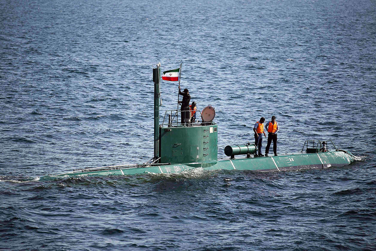 Egy katona zászlót helyez el egy iráni tengeralattjárón a Hormuz-szorosnál tartott haditengerészeti gyakorlaton