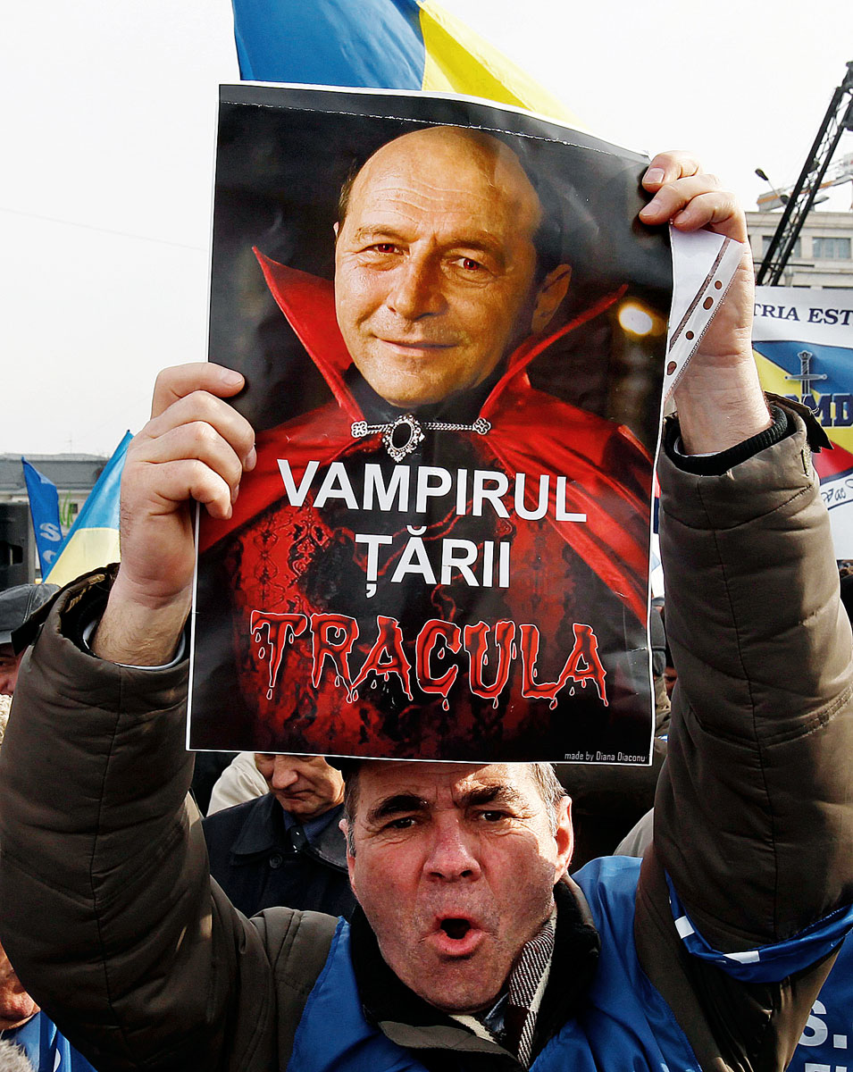 A demonstrator holds a poster mocking Romania's President Traian Basescu as a vampire during a protest at Victoriei square in front of Romania's government headquarters in central Bucharest January 24, 2012. Thousands of Romanians rallied in Buchares