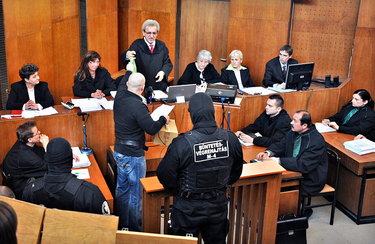 Miszori László, a bírói tanács elnöke csomagot ad át Kiss István másodrendű vádlottnak a romák elleni, hat halálos áldozatot követelő támadássorozat miatt indított büntetőper tárgyalásán