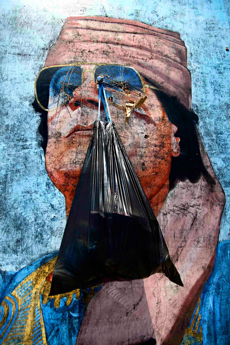 Szemétszállítás Kadhafi óriásportréjával a háttérben Tripoliban. Jelentkezett a múlt
