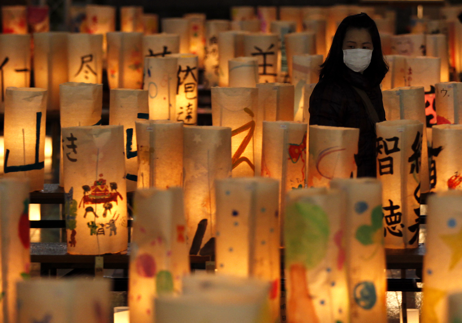 Egy gyászoló halad el Koriyama városában az áldozatok emlékére készített papírlámpások között a földrengés első évfordulóján
