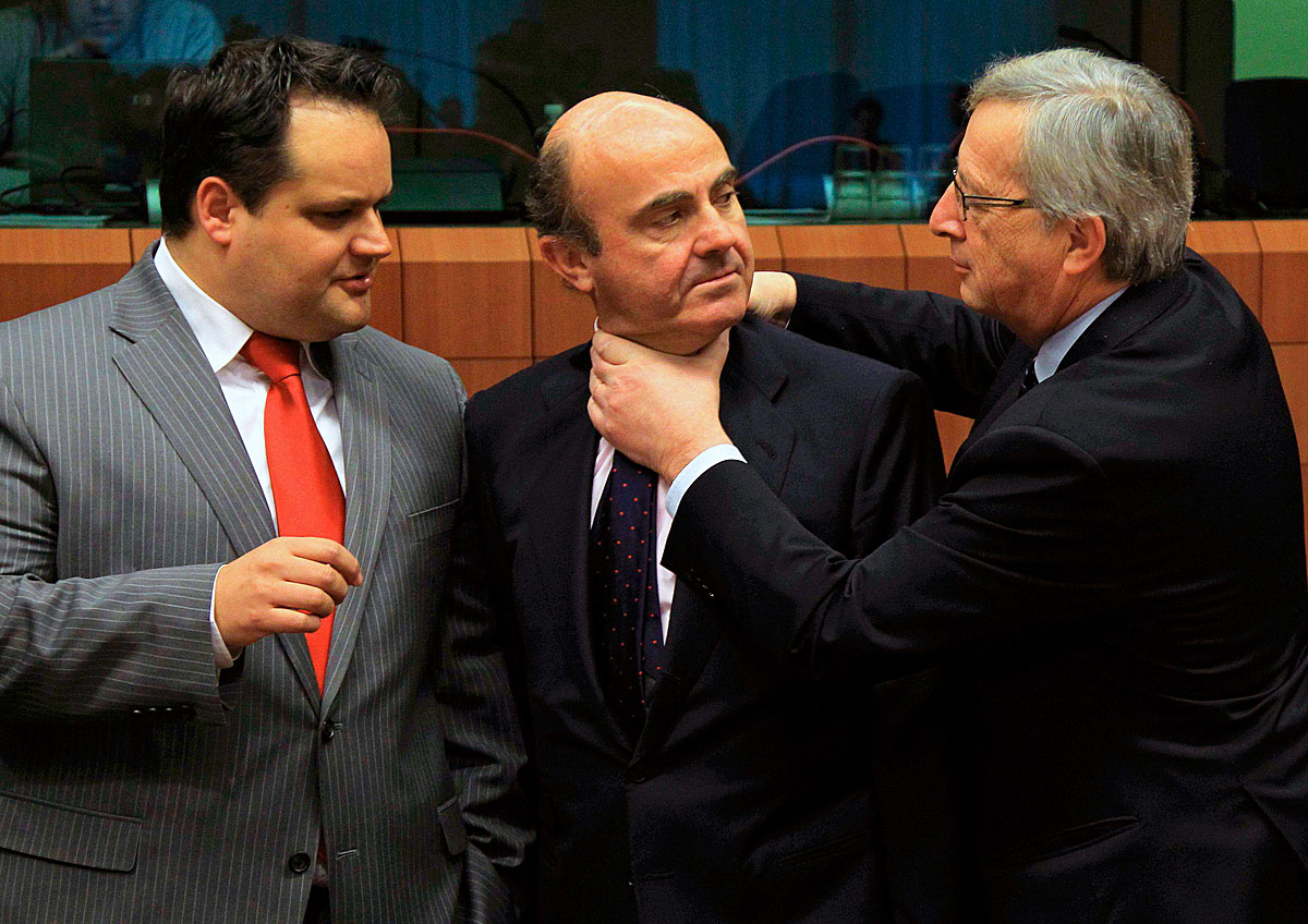 Luis de Guindos spanyol gazdasági miniszter (középen) fogadtatása Brüsszelben. A fojtogató Jean-Claude Juncker luxemburgi kormányfő, Eurogroup-elnök, a néző Jan Kees de Jager holland pénzügyminiszter