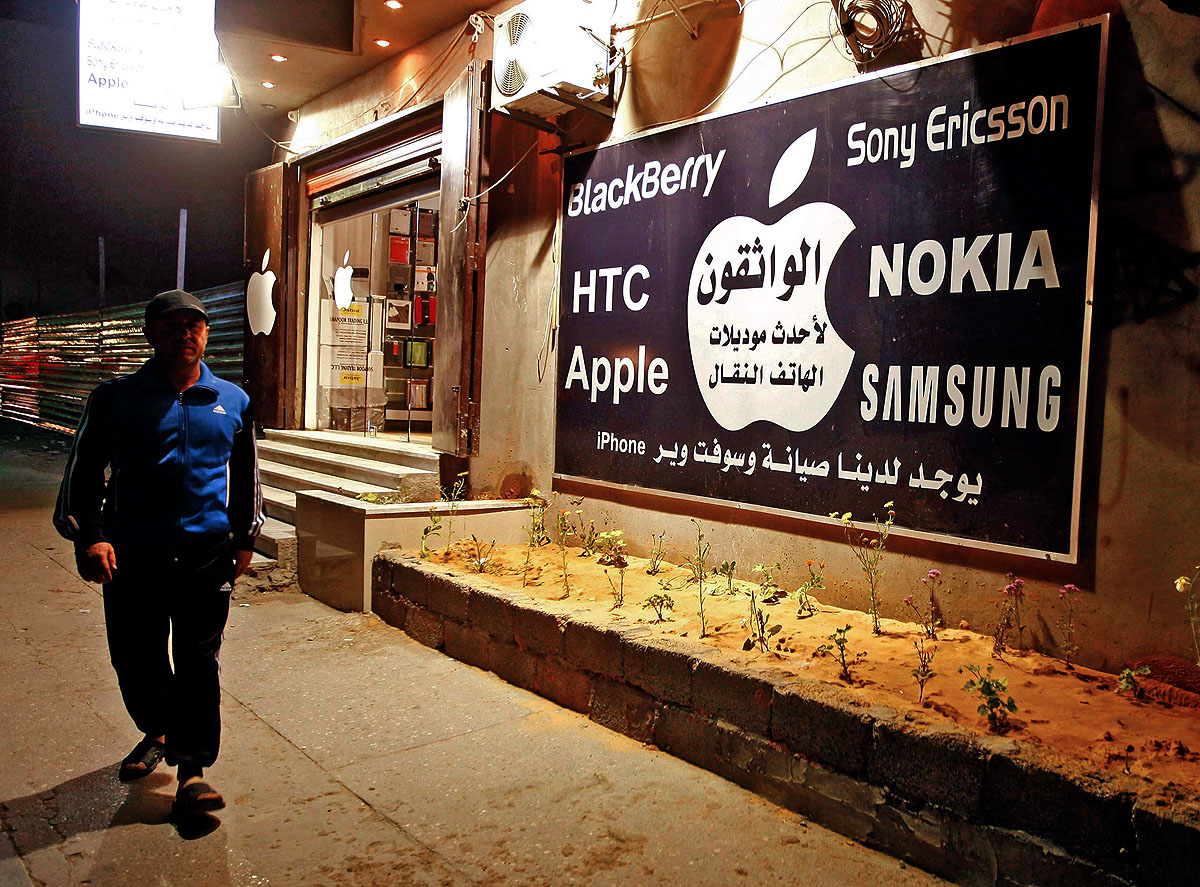 Egy férfi sétál egy tripoli elektronikai szaküzlet és annak reklámja előtt