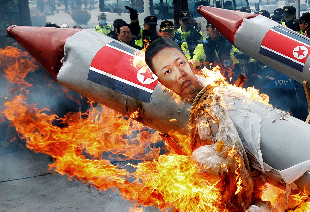 Dél-koreai rendőrök figyelik, ahogy tüntetők felgyújtanak egy papírból készült rakétát Kim Dzsong Un bábújával. Az igazi kilövés sem volt sokkal sikeresebb