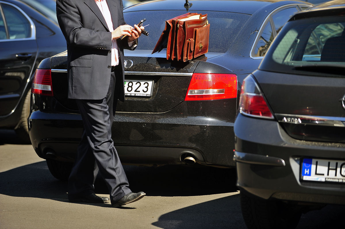 Kormányzati Audi mellett mobilozik egy férfi a parlament parkolójában