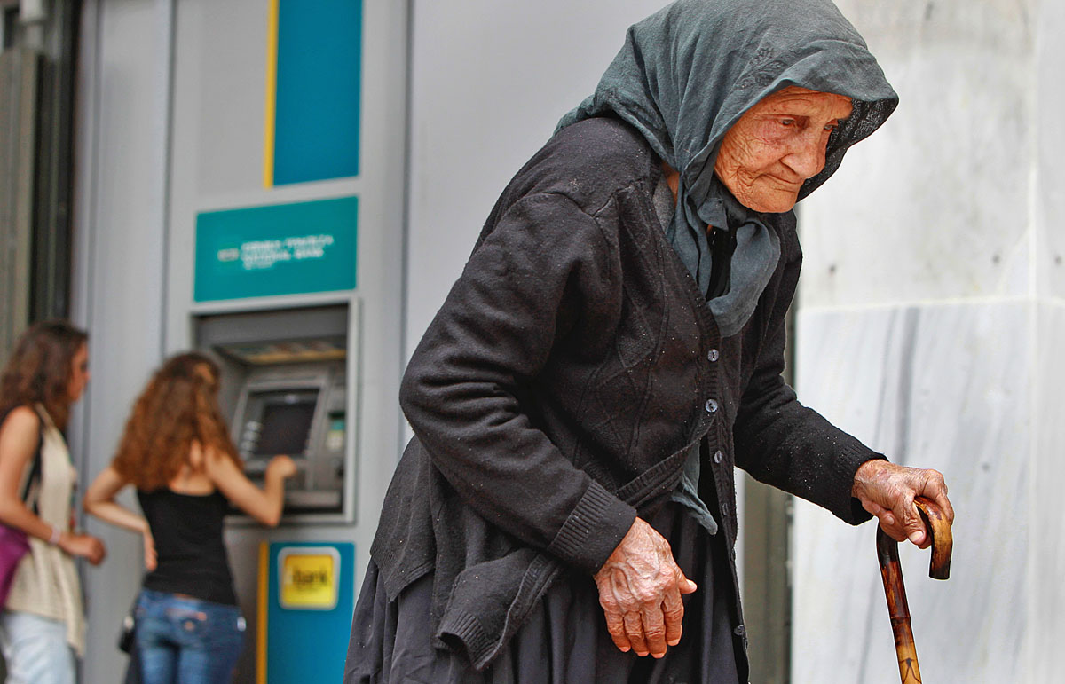 Idős asszony egy athéni pénzkiadó automata előtt