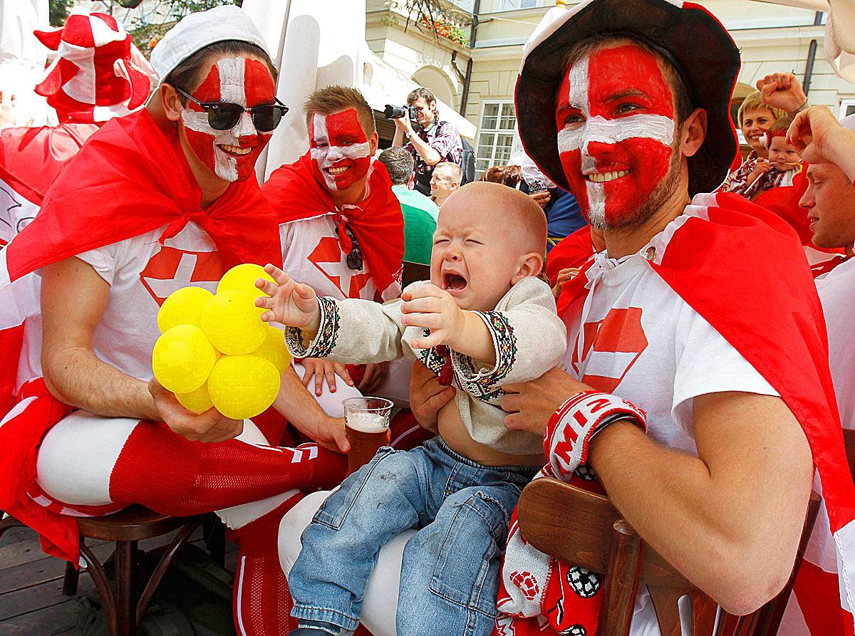 A Ukrainian baby boy cries as he sits with Denmark soccer fans for a photo, in Lviv June 13, 2012. Denmark will play match of the Euro 2012 soccer championships against Portugal in Lviv today.   REUTERS/Gleb Garanich (UKRAINE  - Tags: SPORT SOCCER)