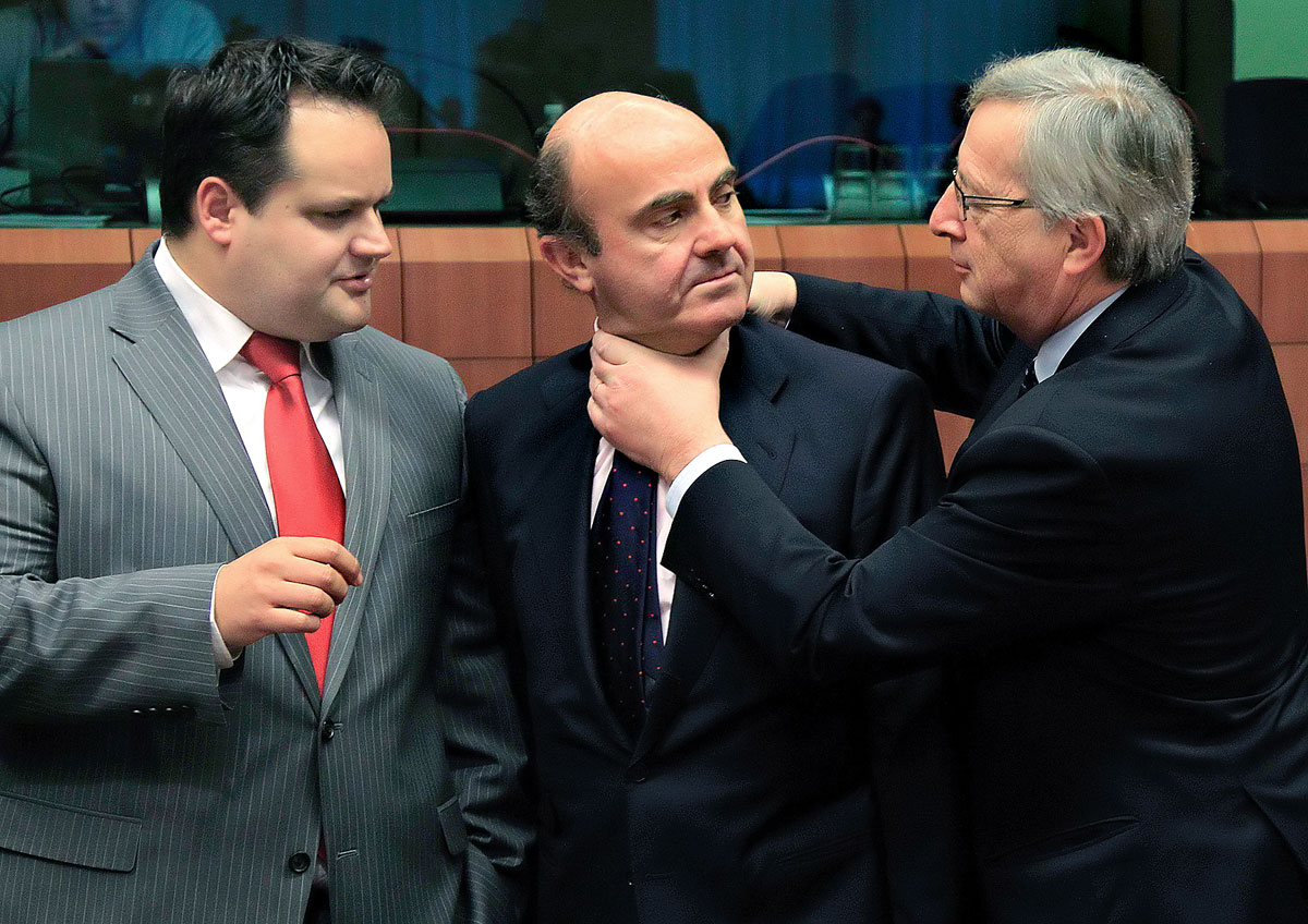 Jean-Claude Juncker luxemburgi miniszterelnök, az Eurogroup elnöke a megszorítást mutatja be Luis de Guindos spanyol gazdasági miniszteren – Jan Kees de Jager holland pénzügyminiszter tekintetétől kísérve – az Eurogroup brüsszeli tanácskozásán
