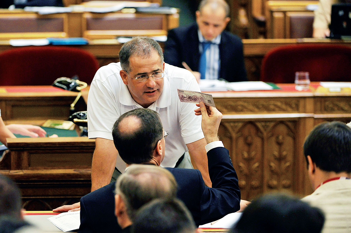 Varga Mihály egy pénzmintát nézeget a parlamentben