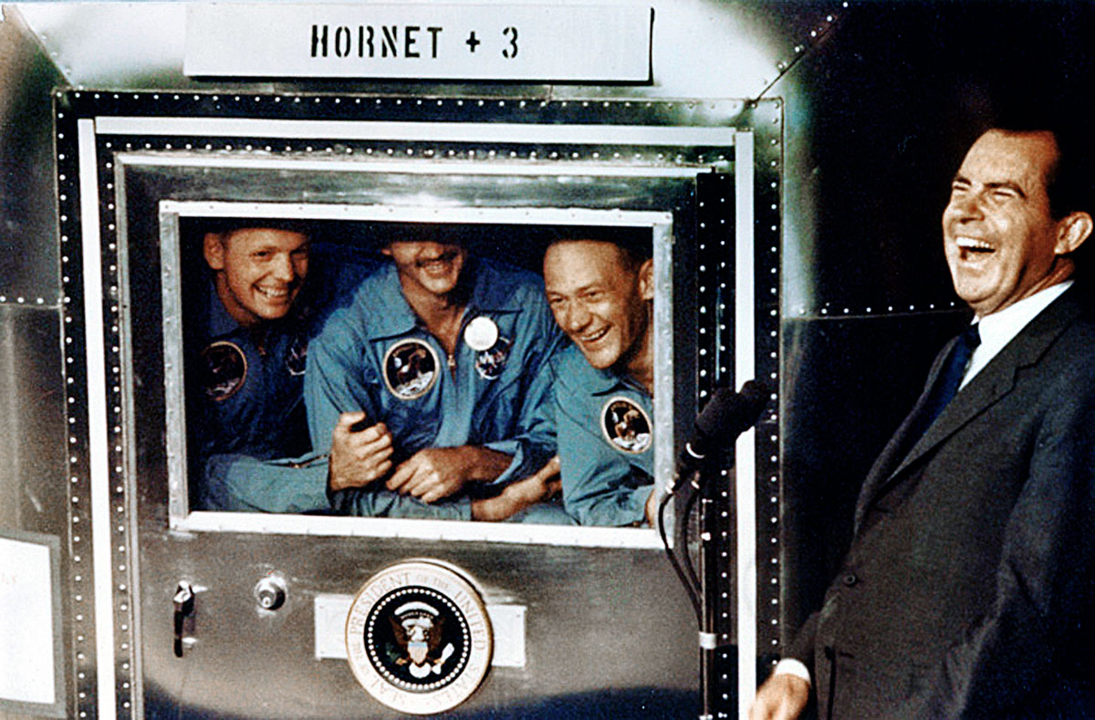 Az Apollo–11 legénysége – balról jobbra Armstrong, Collins, Aldrin – és Nixon elnök az izolációs kabinon kívül a visszatérés után