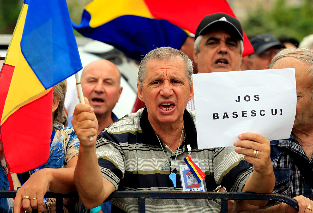 An anti-Basescu protester holds a banner reading 