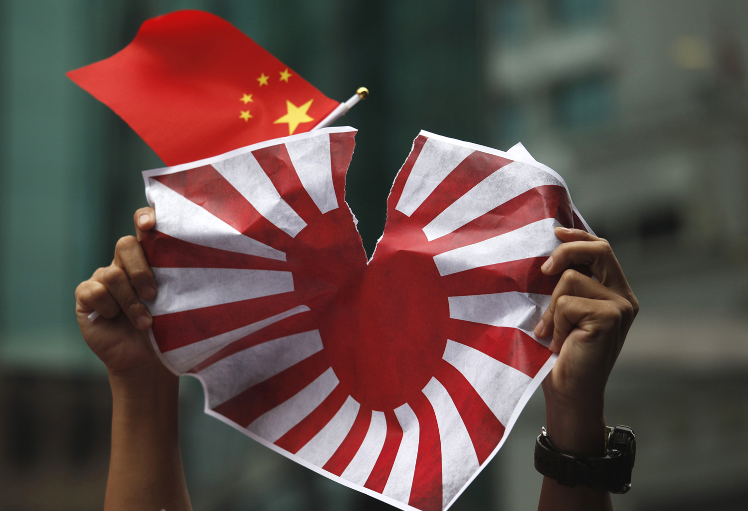 A háborús japán zászló másolatát tépi szét egy kínai tüntető egy augusztusi demonstráción