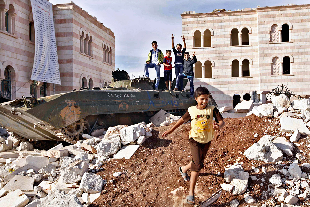 Children play on a destroyed armoured personnel carrier belonging to forces loyal to Syria\'s President Bashar al-Assad in Azaz, in northern Syria near the border with Turkey, October 8, 2012. REUTERS/Zain Karam (SYRIA - Tags: CIVIL UNREST POLITICS C