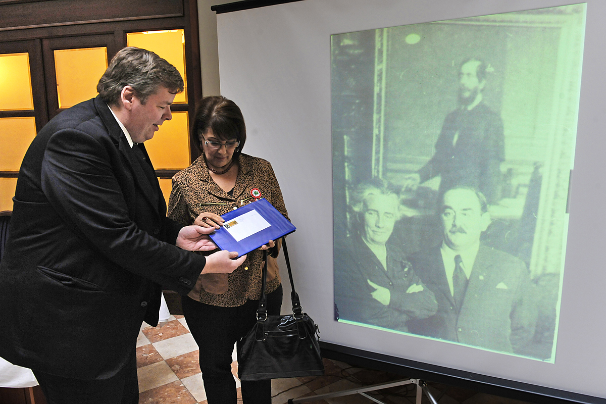 Schmuck Andor és Jánosi Katalin nézik a bélyeget, mellettük kivetítőn a megtalált fotó