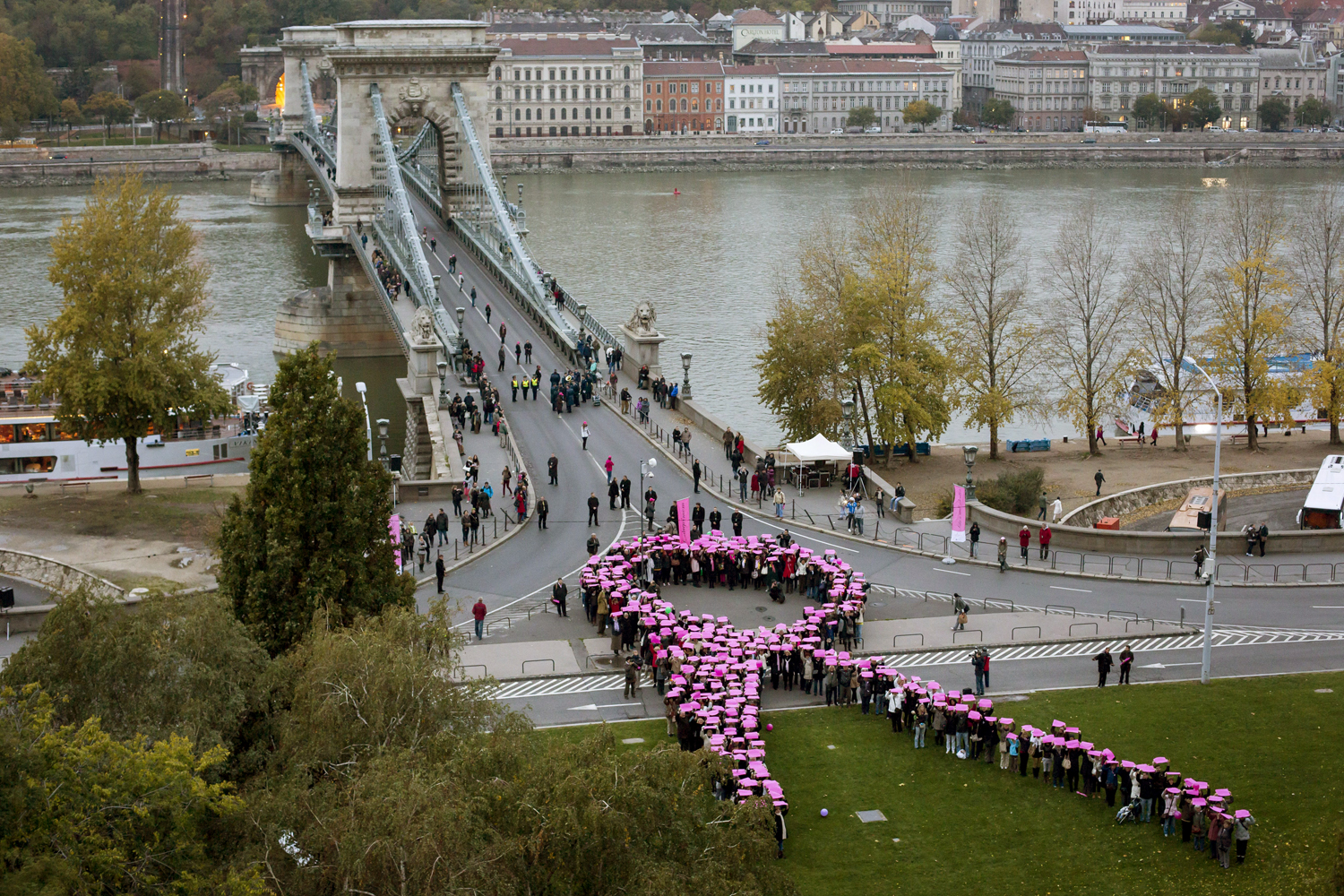 Résztvevők a mellrák elleni küzdelem nemzetközi jelképét, rózsaszín szalagot formáznak a budapesti Széchenyi téren