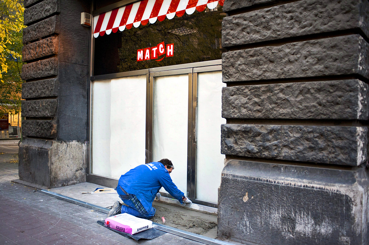 Egy munkás betonoz a fővárosi Ferenciek téri volt Match üzlet kirakatánál