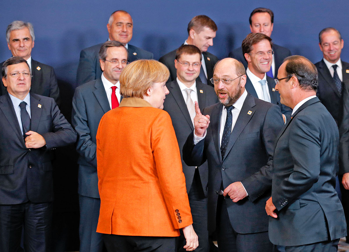 Eligazítás csoportkép előtt. A német kancellár, az Európai Parlament elnöke és a francia elnök vitáját figyelik az európai állam- és kormányfők a brüsszeli csúcson