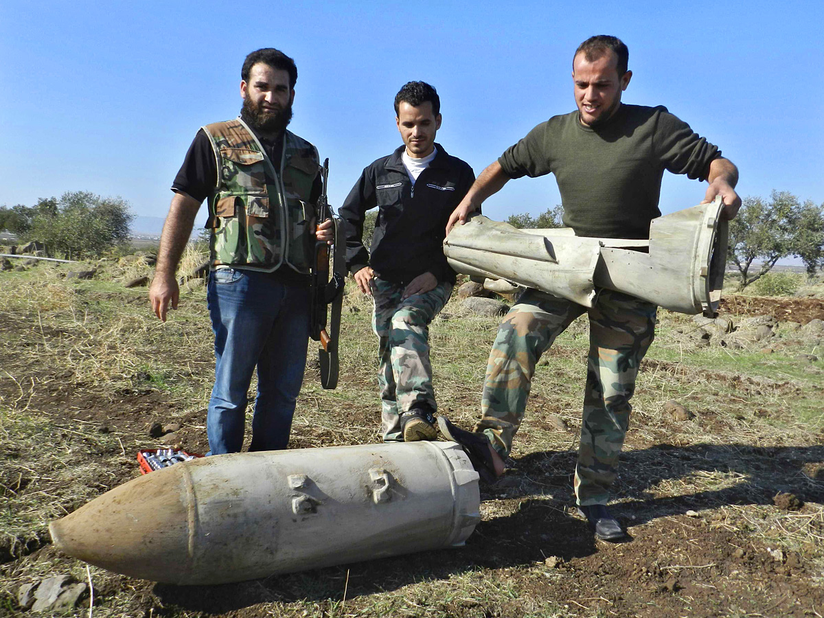 A Szabad Szíriai Hadsereg tagjai egy bombával a szír légierő támadása után Hulában