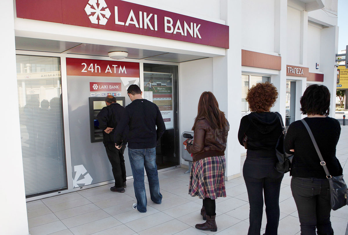 A Laiki Bank bankjegykiadó automatájánál állnak sorban a ciprusi Larnacában 2013. március 16-án. Hajnalban az euróövezeti országok pénzügyminisztereinek megállapodása szerint Ciprus 10 milliárd eurós mentõ hitelcsomagot kap, de cserébe többek között