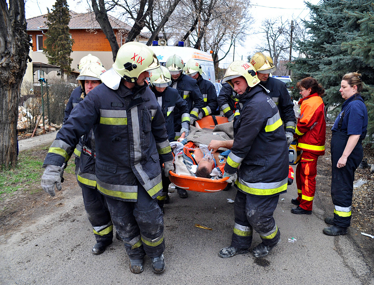 Tűzoltók hordágyon viszik a mentőhelikopterhez a sérültet