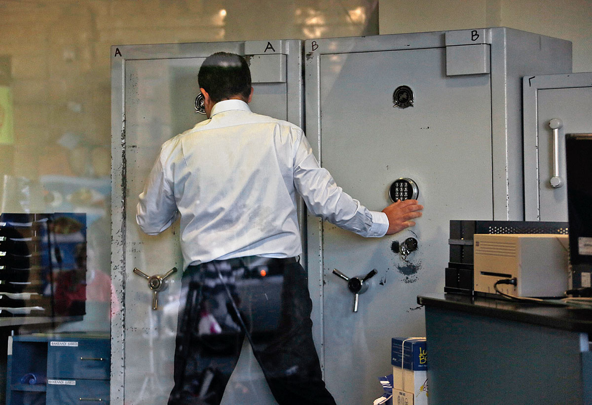 An employee opens a safe inside a Bank of Cyprus branch before it opened in Nicosia March 28, 2013. Cypriots are expected to descend in thousands on banks, which reopen on Thursday, with tight controls imposed on transactions to prevent fleeing depos