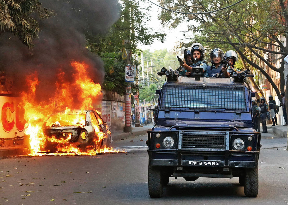 A police van passes a burnt vehicle after activists of Bangladesh Nationalist Party (BNP) set fire to it during a clash in Dhaka March 2, 2013. Activists and supporters of the main opposition BNP torch and vandalise vehicles as they clash with police