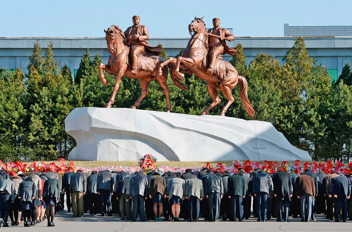 Észak-koreaiak a Nagy Vezér, Kim Ir Szen (balra) és fia, a Kedves Vezető, Kim Dzsong Il szobra előtt