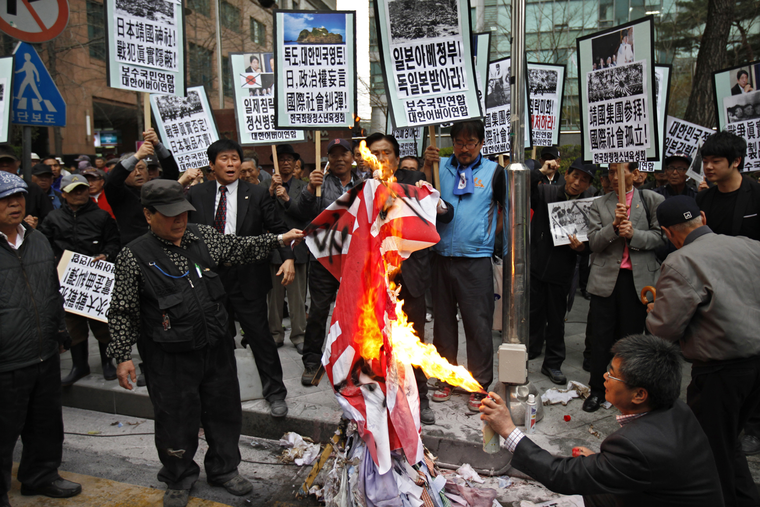 A szöuli japán nagykövetség előtt feldühödött dél-koreaiak a világháborús császári lobogót égetik
