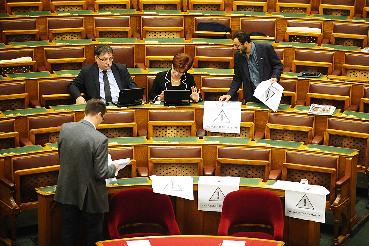 Párbeszéd Magyarországért képviselői trafikügyes papírokat helyeznek el a Fidesz padsoraiban, a Parlament plenáris ülése előtt