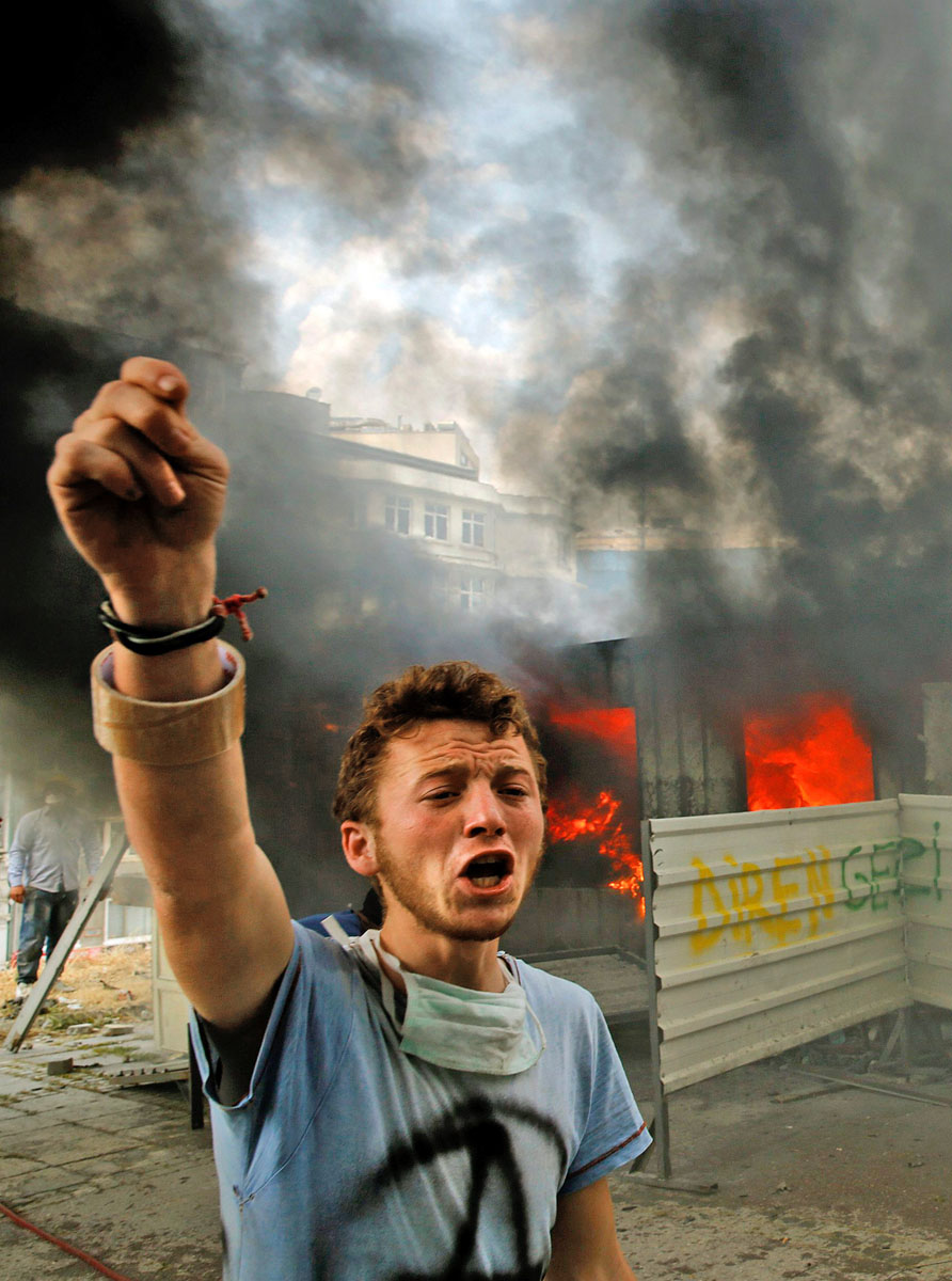 Kormányellenes tüntető kiált segítségért egy égő konténer eloltásához az isztambuli Taksim téren