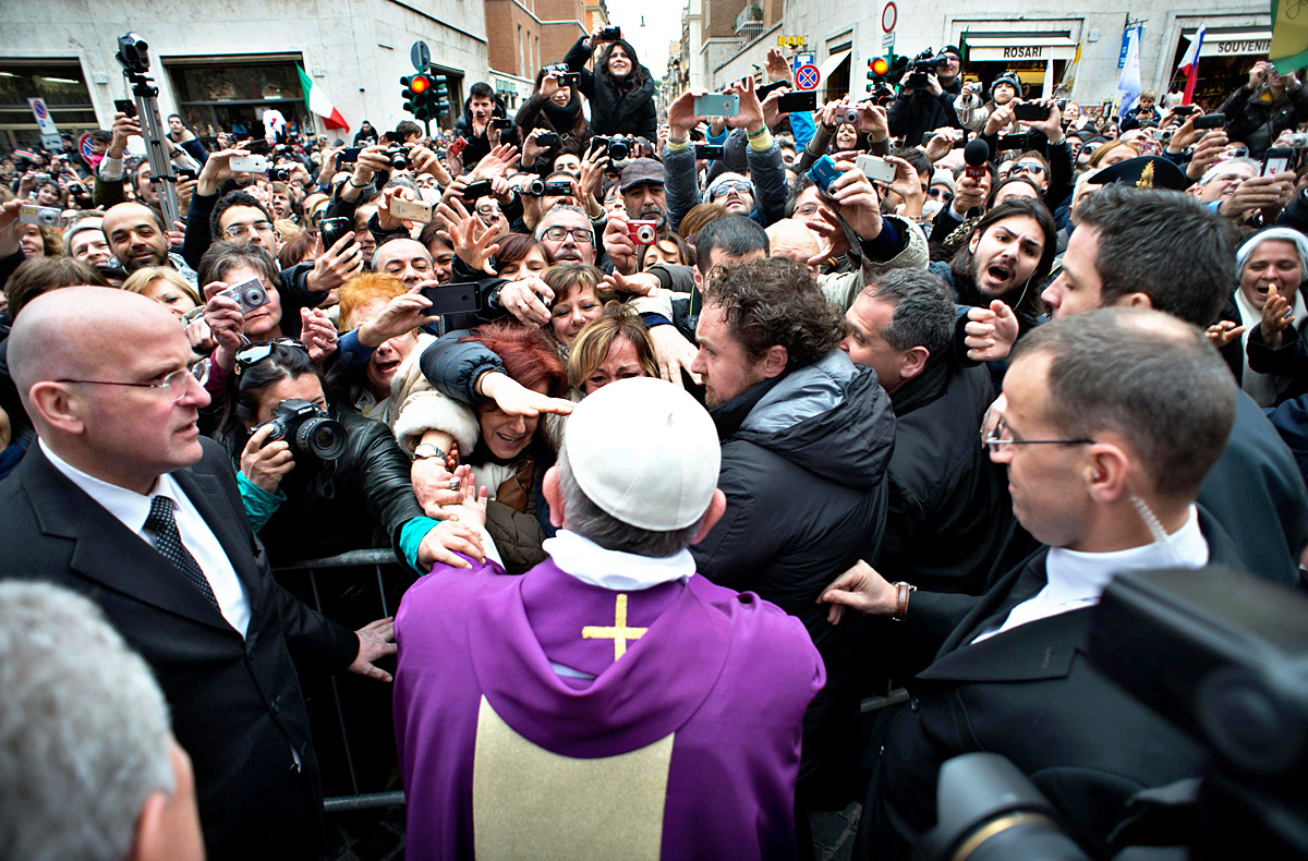 Ferenc hívőket üdvözöl a vatikáni Szent  Anna-templom előtt. Szereti a közvetlenséget