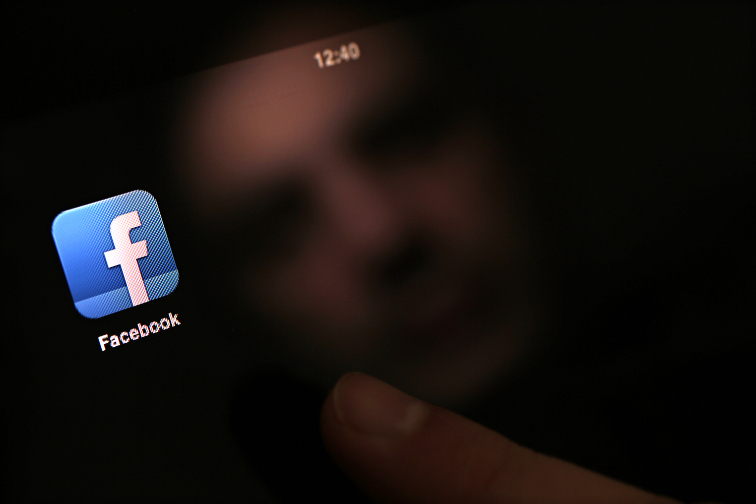 Mindig elérhető: egy férfi elindítja a Facebook-alkalmazást iPad-jén