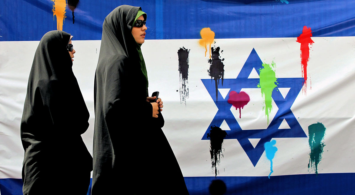 Színes festékkel megdobált izraeli zászló mellett halad el két muzulmán asszony az évenkénti al-Kudsz, azaz Jeruzsálem napja alkalmából tartott ünnepségen Teheránban, az iszlám szent böjti hónap, a ramadán utolsó péntekjén