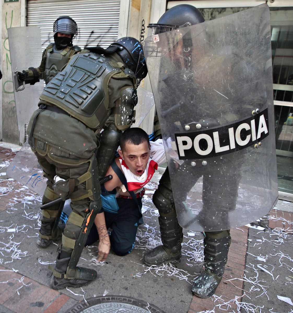 Egy tüntető és a rohamrendőrök Bogotában