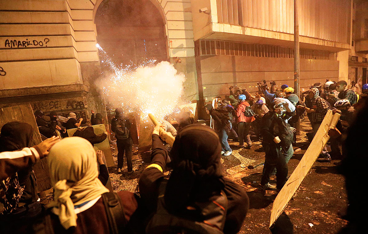 A Fekete Blokkhoz (Black Bloc) tartozó tüntetők petárdát lőnek ki a riói önkormányzat épületére
