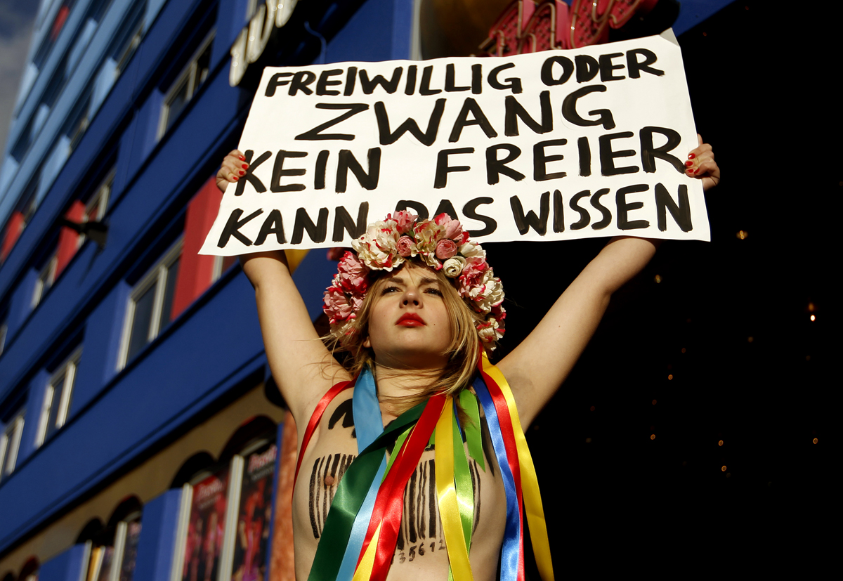 Önként vagy kényszer hatására: ezt a szexért fizető férfi nem tudhatja  - olvasható egy Femen-aktivista plakátján Európa legnagyobb bordélyháza előtt Kölnben