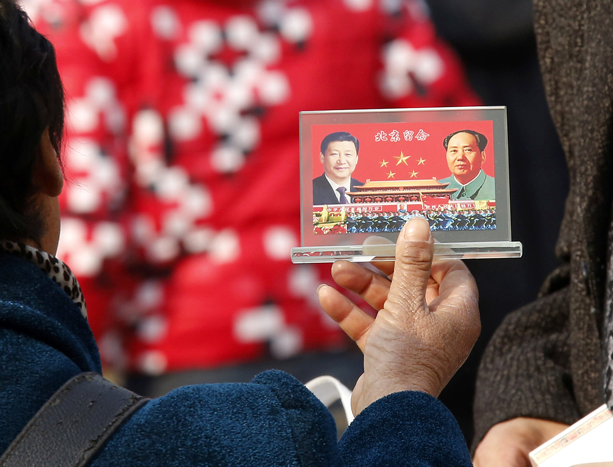 Utcai árus Mao Ce-tung és más kínai vezetők képével díszített szuvenírt kínál Pekingben