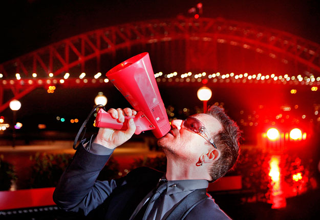 A U2 frontembere pózol az AIDS Elleni Küzdelem Világnapja alkalmából vörösben úszó Harbour Bridge előtt, Sydneyben, 2010-ben 