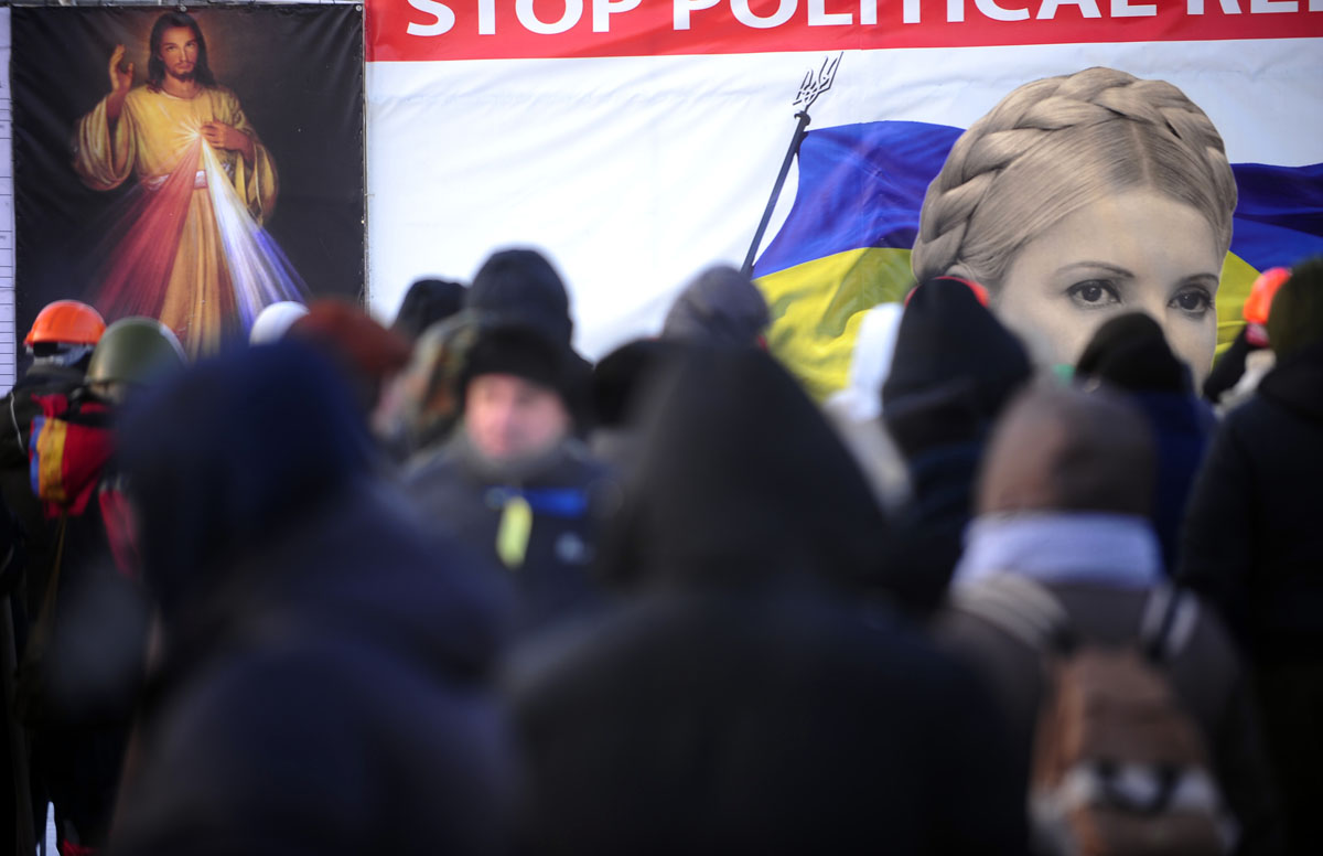 Emberek a bebörtönzött exkormányfő, Julija Timosenko egyik kijevi plakátja előtt. Csak akkor mennek el a térről, ha meggyőződtek a hatalom teljes átalakításáról