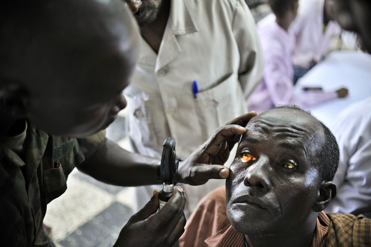 Ugandai orvos vizsgál egy férfit, akit szegénysége elzár az alapszintű egészségügyi ellátástól is