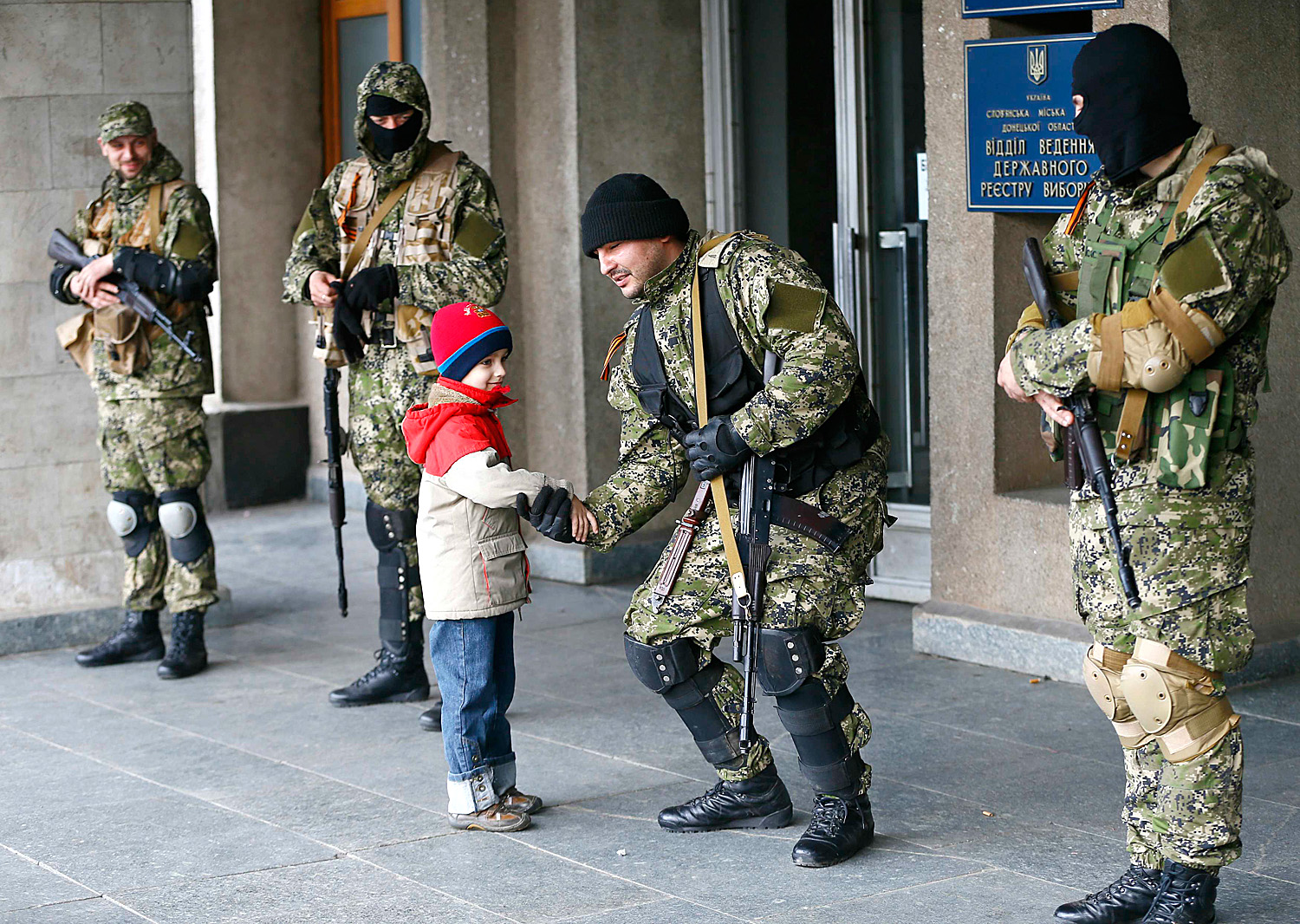 Szlovjanszki kisgyerek kezet nyújt egy épületfogalaló orosz fegyveresnek a polgármesteri hivatal előtt
