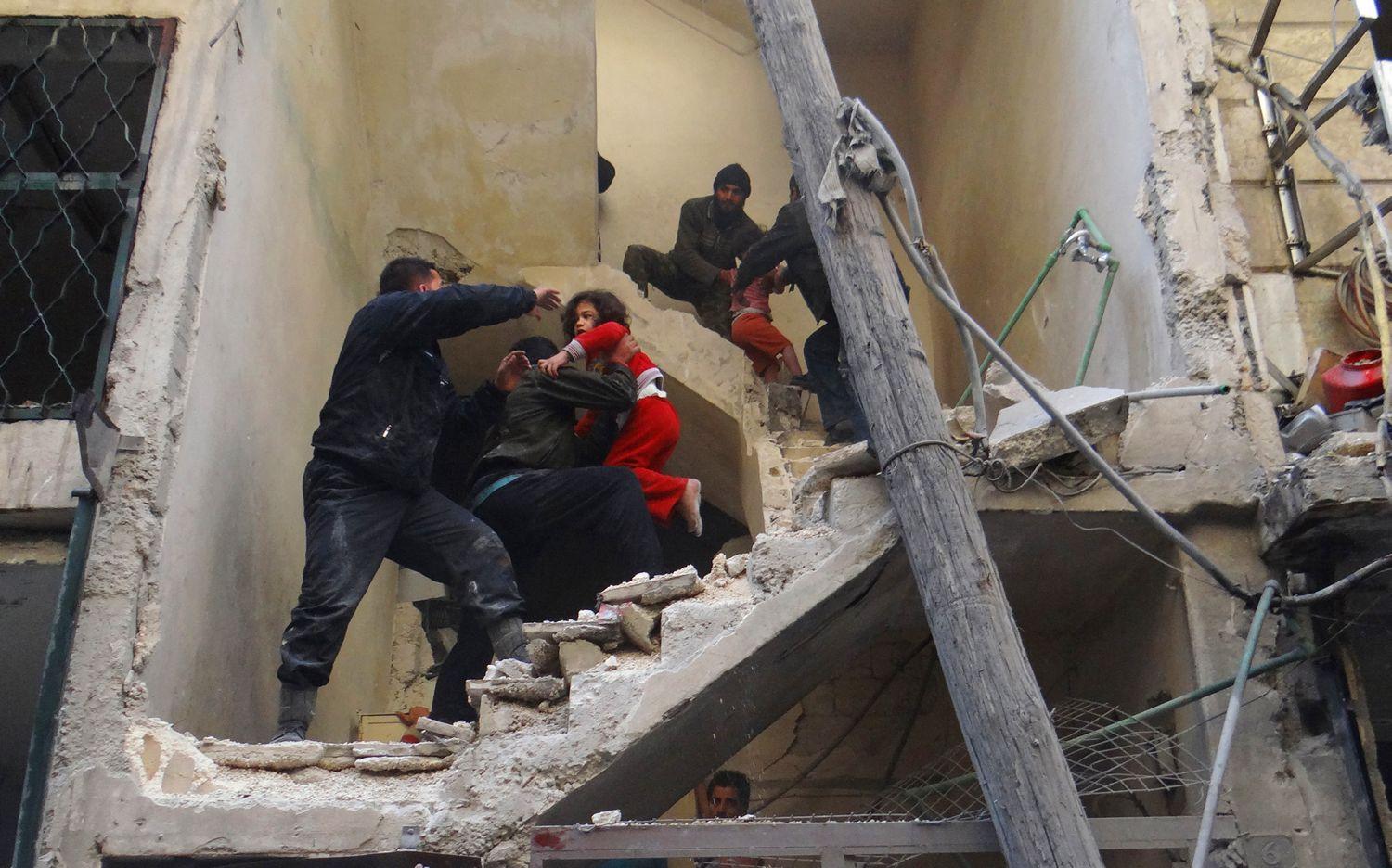 Gyerekeket menekítenek egy lebombázott házból Aleppóban