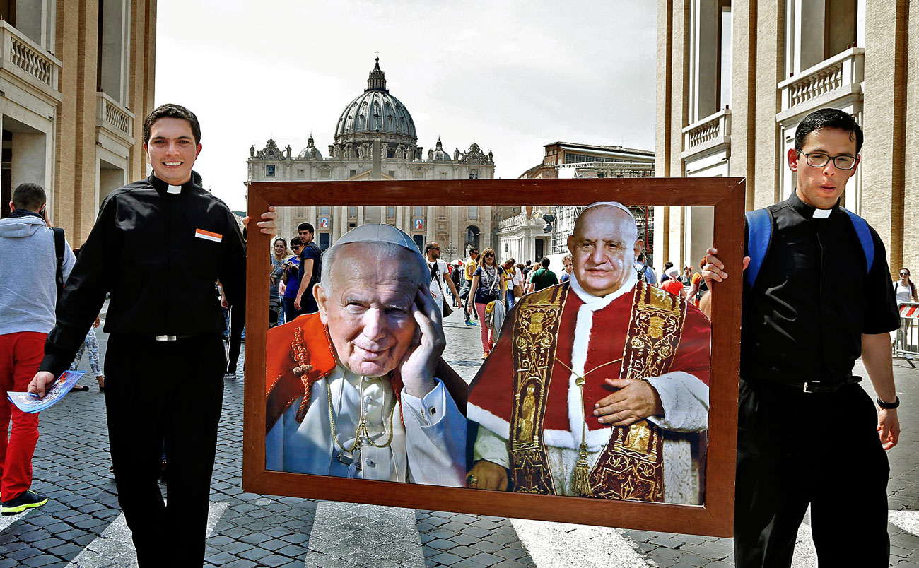 II. János Pál és XXIII. János pápa portréját viszik papok a római Szent Péter téren