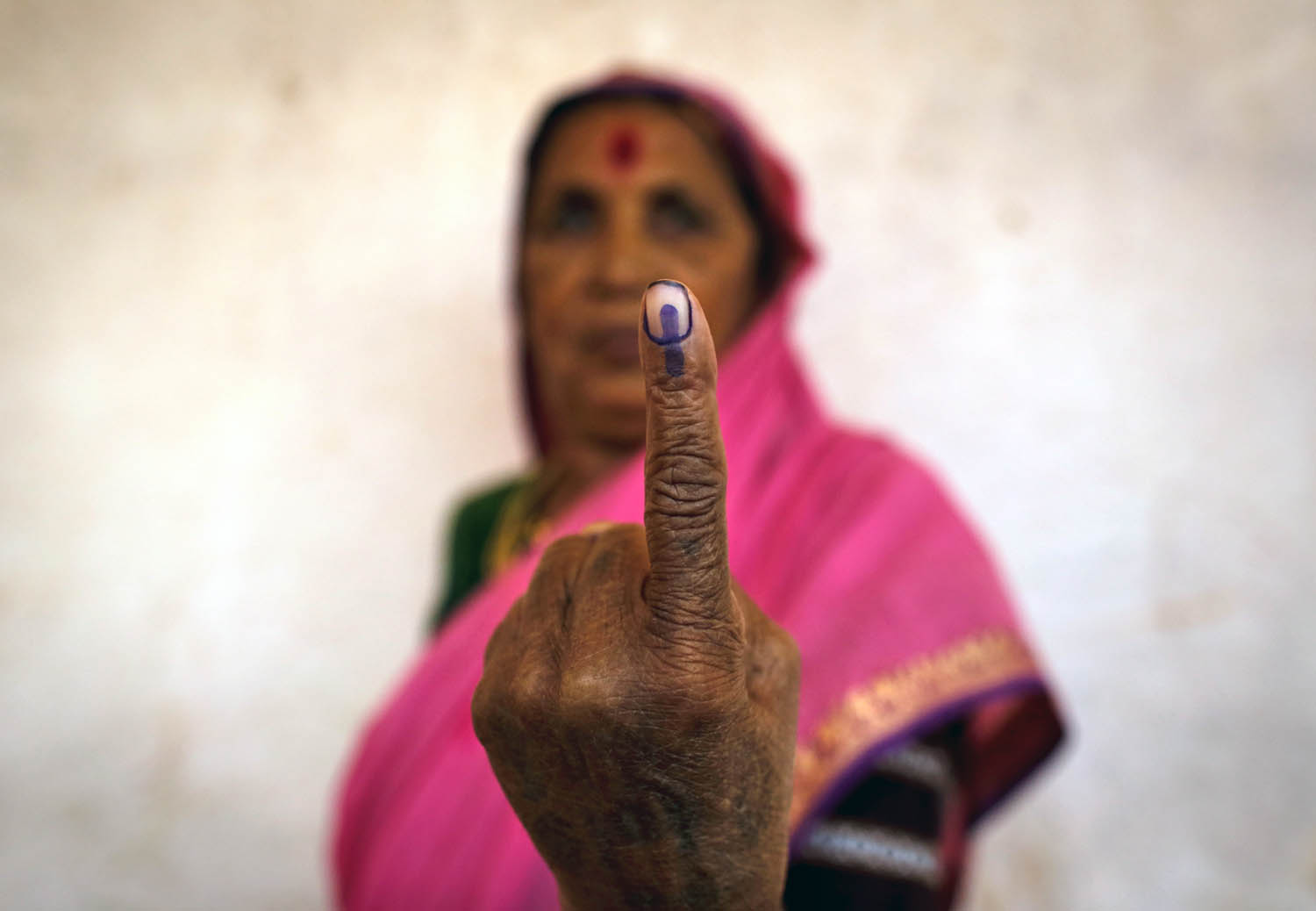 Falusi asszony mutatja a szavazáskor festékbe mártott ujját