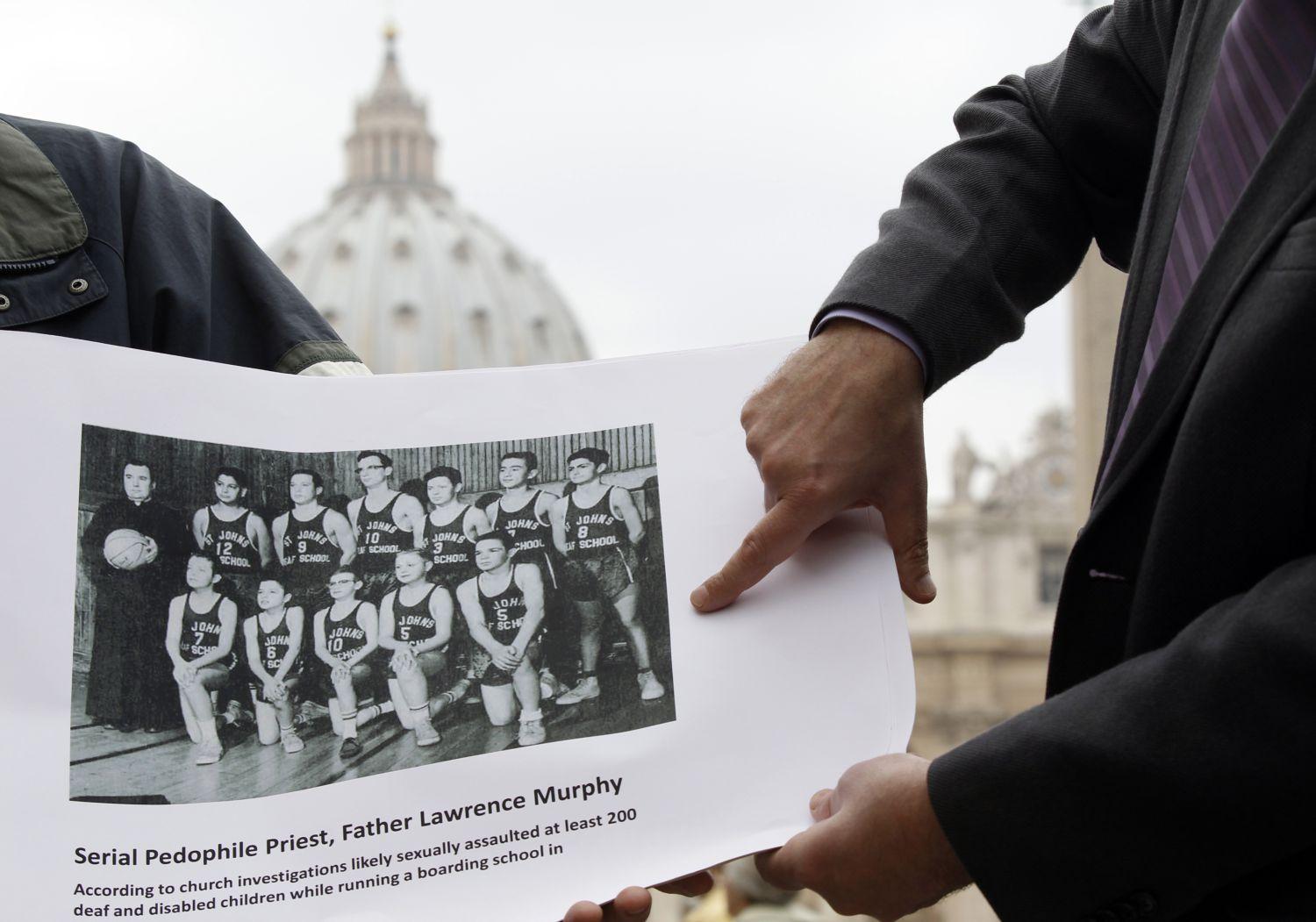 Lawrence Murphy szexuális zaklatással vádolt amerikai pap fotóját mutatja a St John'S süketek iskolájának kosárlabda capatával egy tüntető a Vatikánban