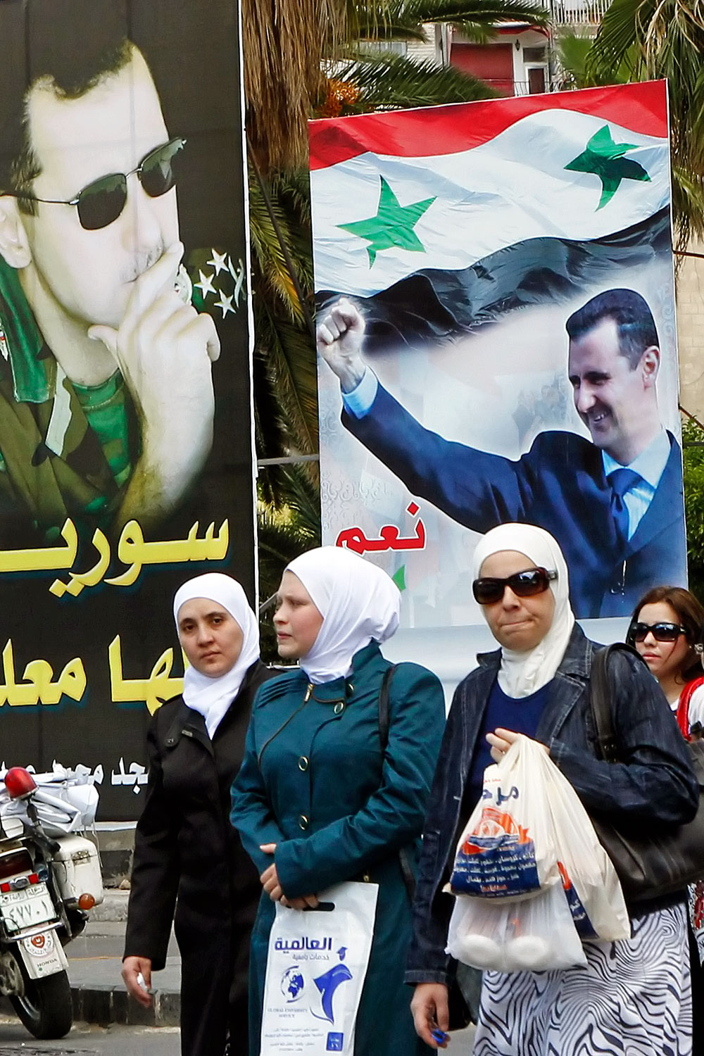Asszonyok mennek Bassár el-Aszad elnök választási plakátjai előtt Damaszkuszban