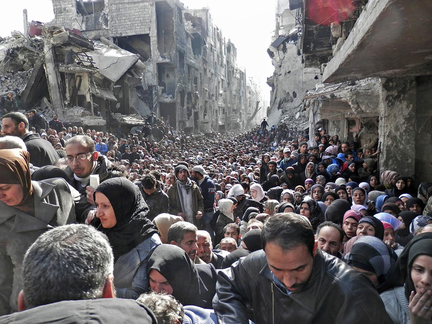 Szír menekültek várnak az ételosztásra Damaszkuszban
