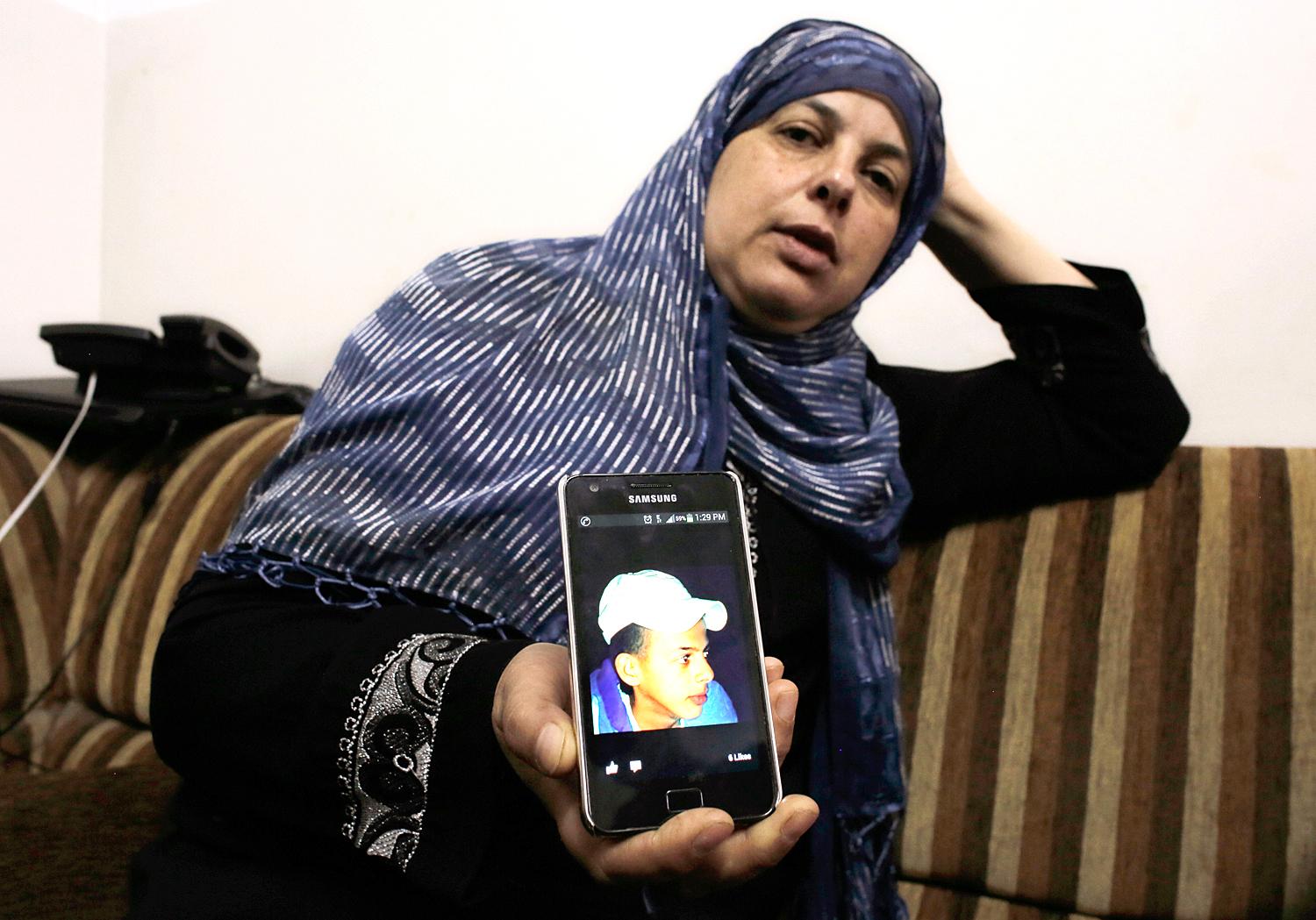 A bosszúgyilkosság áldozatául esett Mohammed Abu Khudair fényképét mutatja mobilján édesanyja